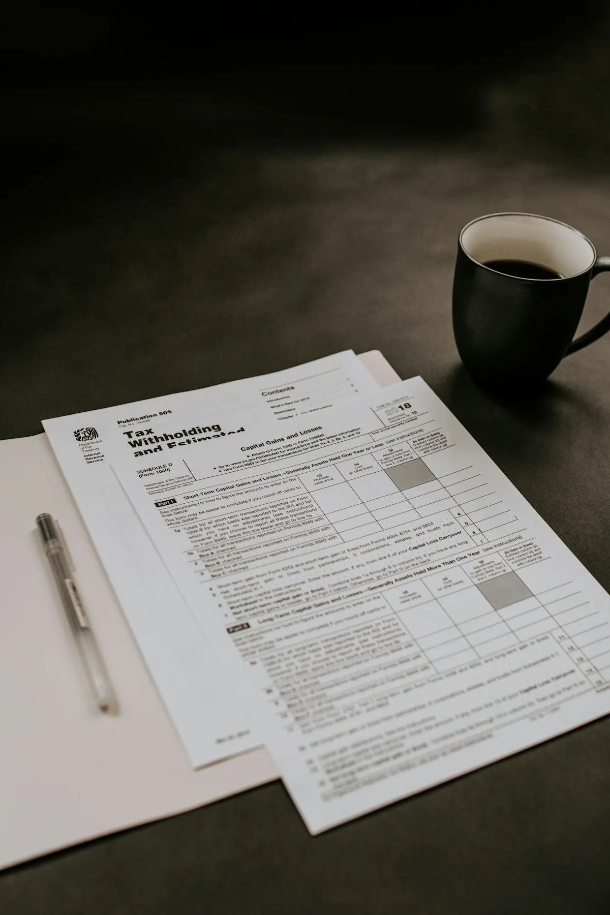 Printed forms, a pen and a cup of coffee on a desk