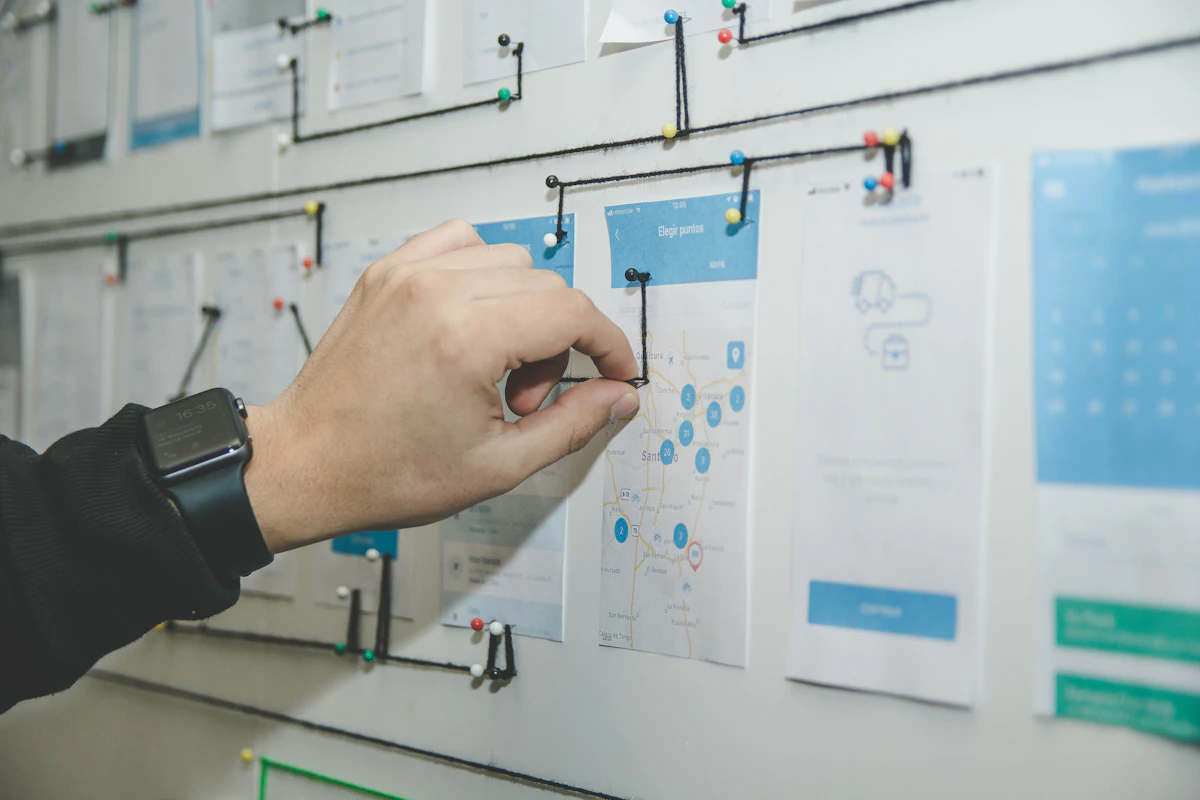 A hand mapping out app screens and steps on a planning wall during a project discovery session