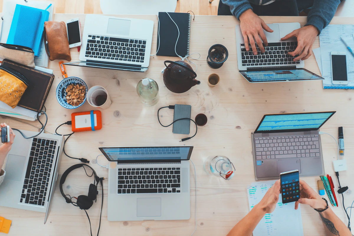 A table covered in laptops, phones and paperwork, the kind of repetitive manual work where AI usually pays off first